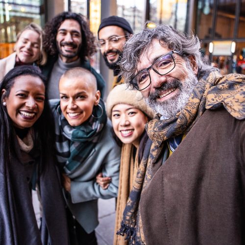 Happy coworkers taking a selfie together outdoors.